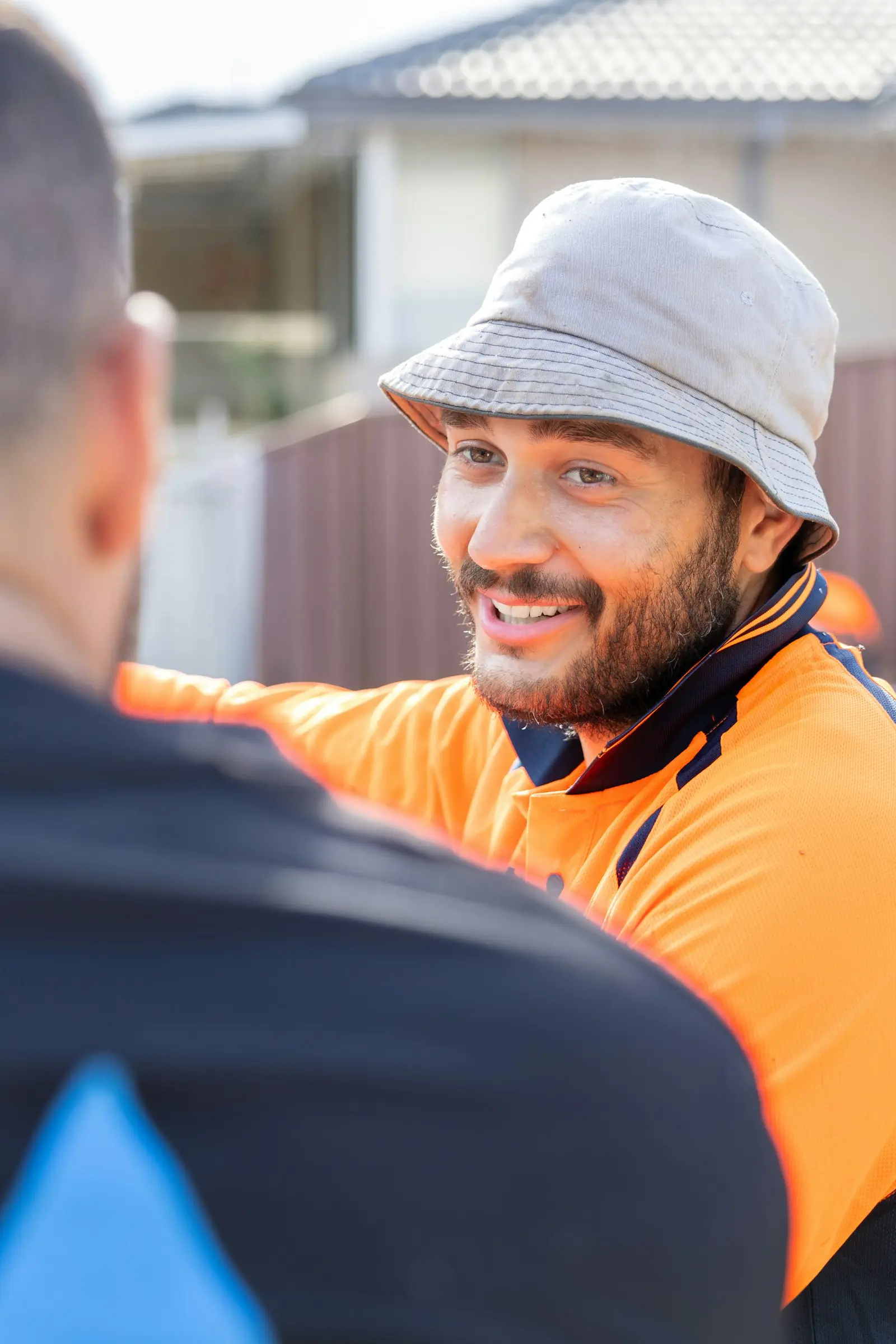 Smiling tradesperson in an orange hi-vis shirt talking with a customer