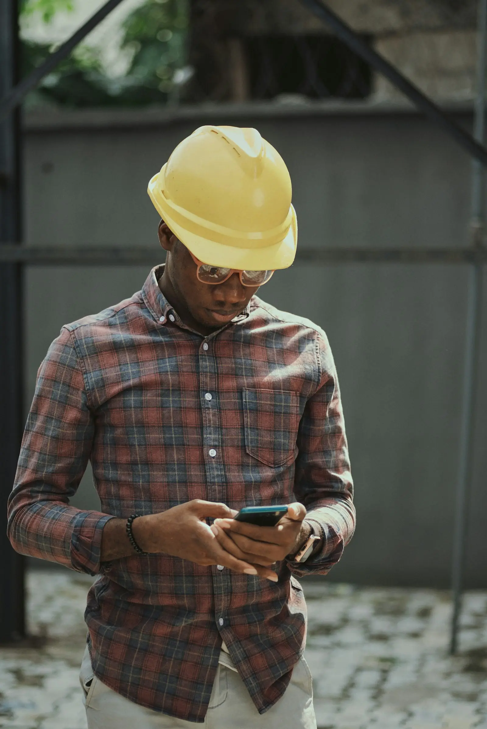 Tradesperson in a hard hat checking a smartphone on site