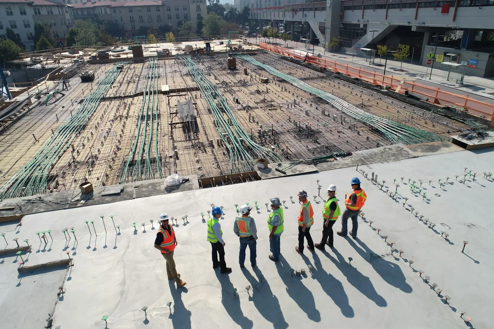 A crew in hard hats and hi-vis vests standing on a concrete slab on a building site
